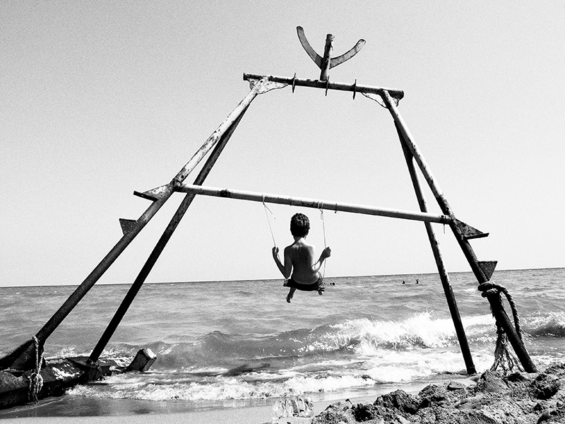 [cml_media_alt id='1637']Foto: un bambino gioca su un’altalena appesa ai resti di un barcone per immigrati. – © Marco Ristuccia[/cml_media_alt]